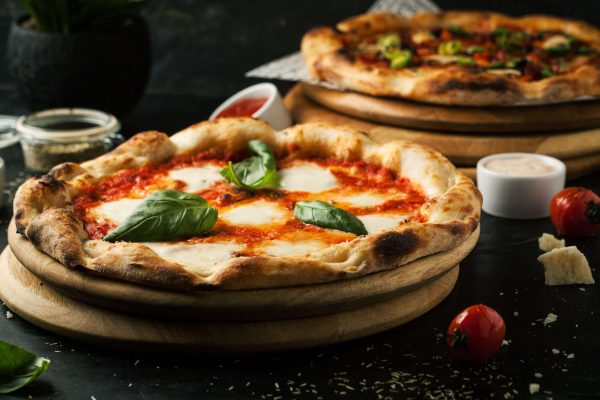 Delicious pizza with mozzarella on a wooden board on a dark background